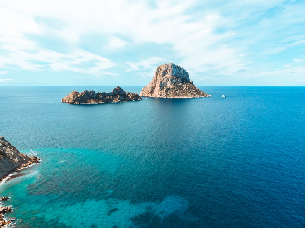 Formación rocosa gris y marrón en el mar azul bajo el cielo azul durante el día