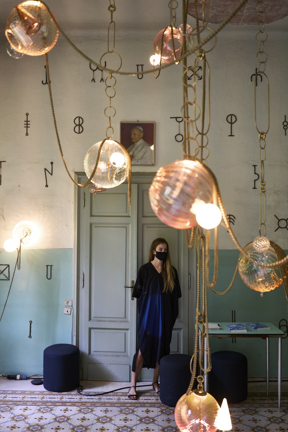 a woman standing in a room with a chandelier hanging from the ceiling