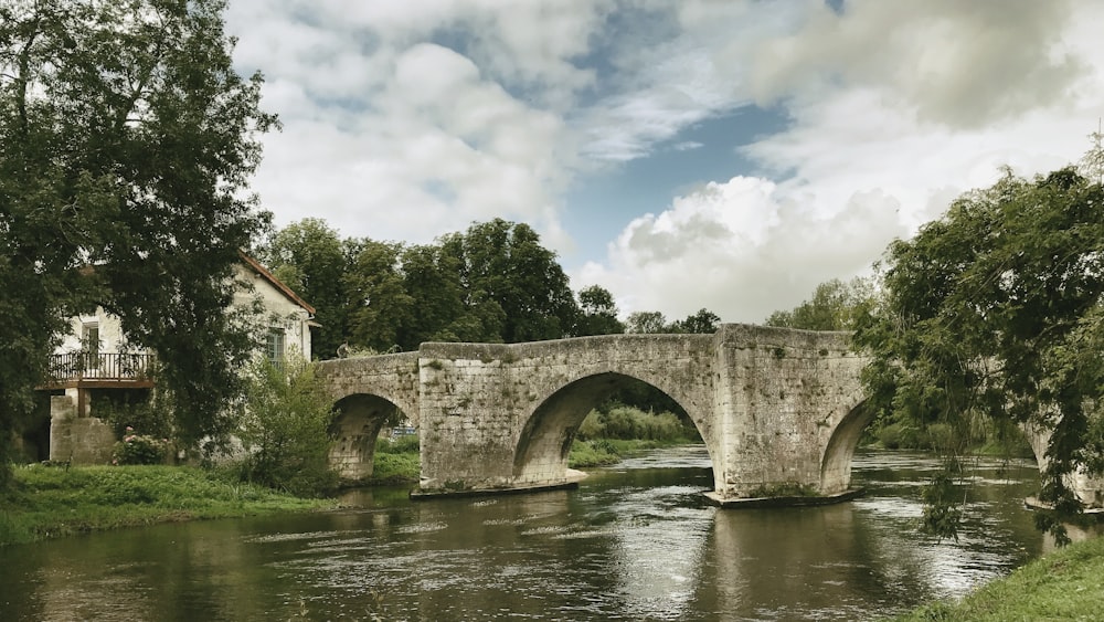 puente de hormigón gris sobre el río bajo el cielo azul y las nubes blancas durante el día