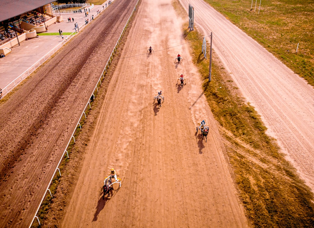 a group of people riding horses down a dirt track