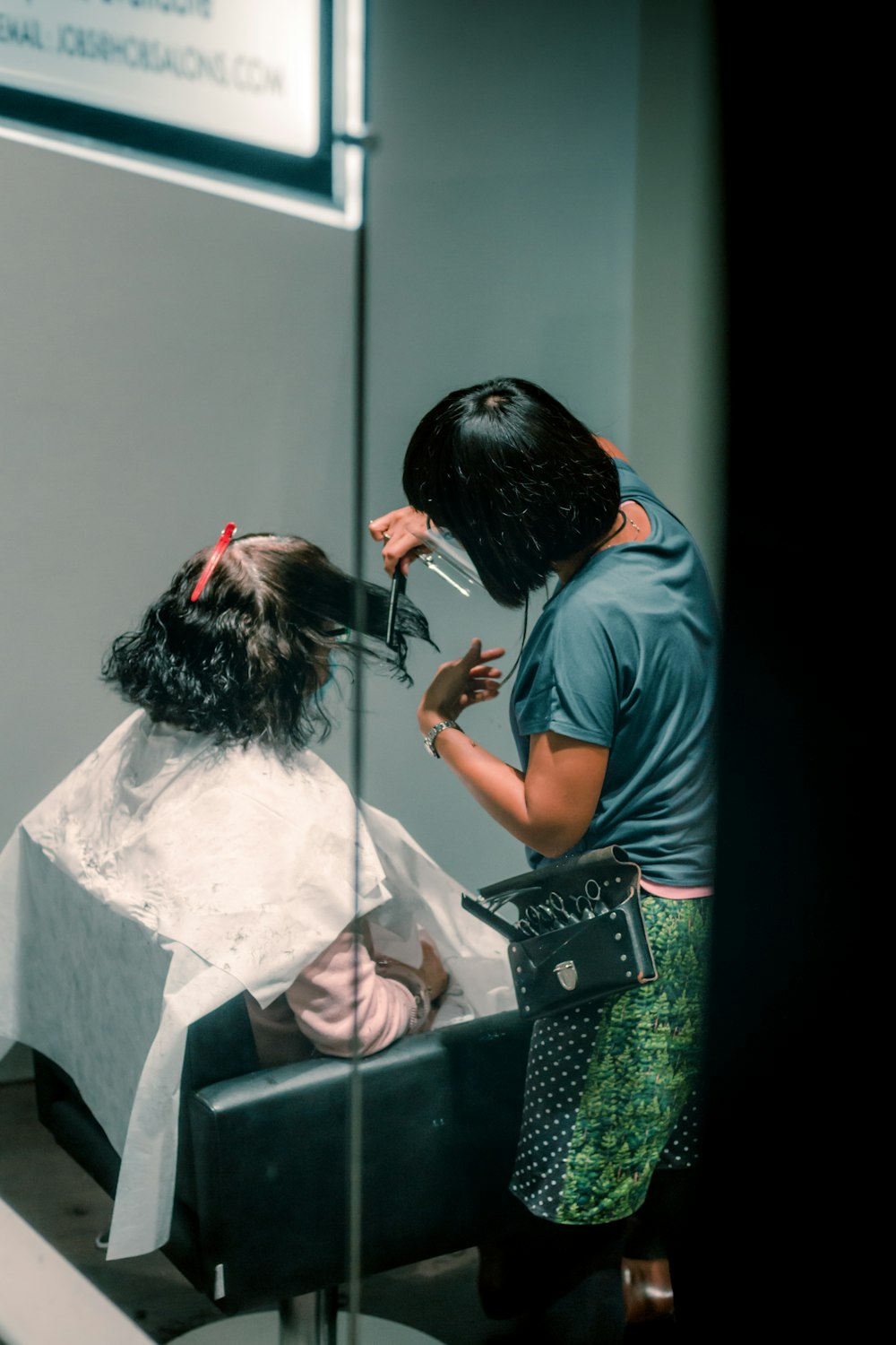 a woman cutting another woman's hair in a salon