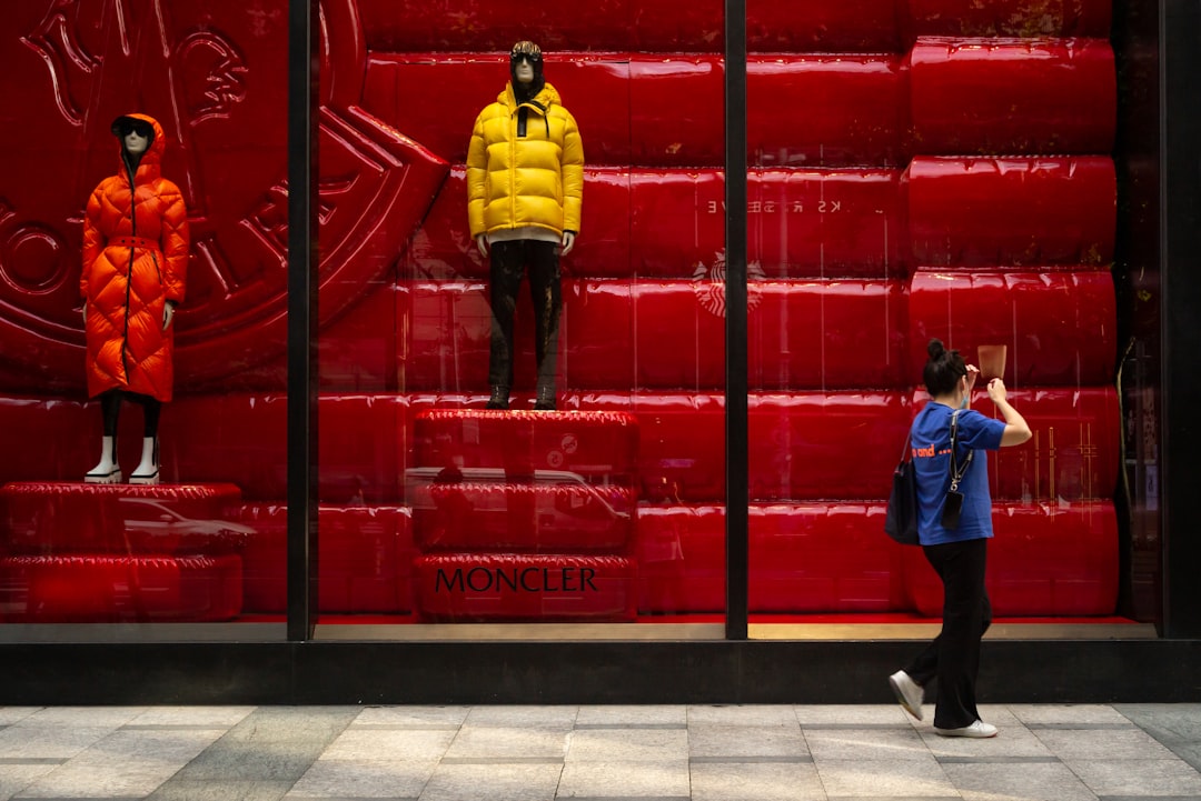 man in yellow and black jacket standing beside red metal gate,