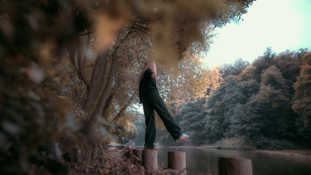 woman in black jacket standing on brown wooden dock during daytime