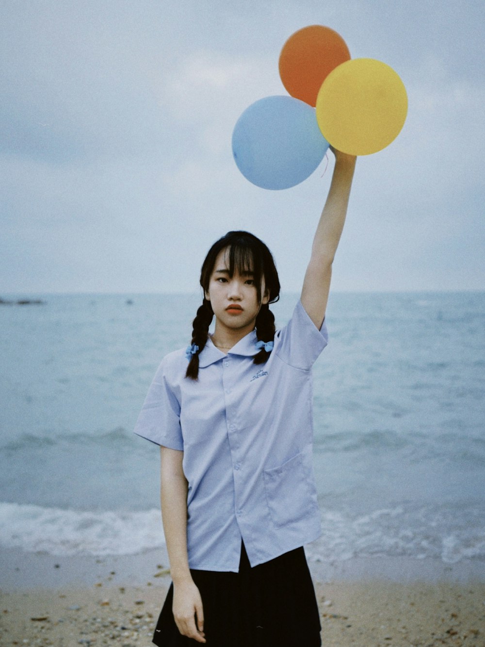 woman in white button up shirt holding blue and white balloons