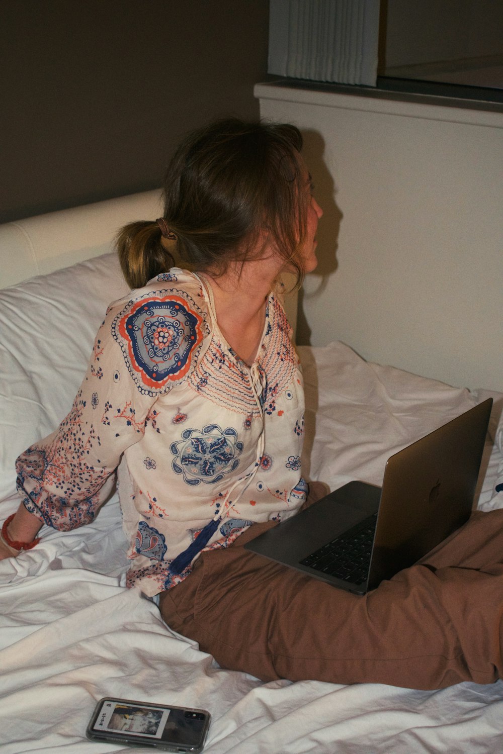 a woman sitting on a bed with a laptop