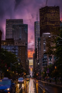 cars on road between high rise buildings during night time