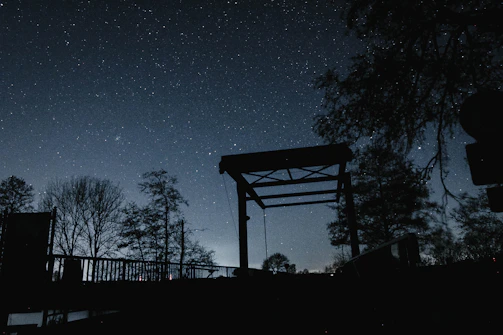 A serene night sky filled with twinkling stars over a calm bridge.
