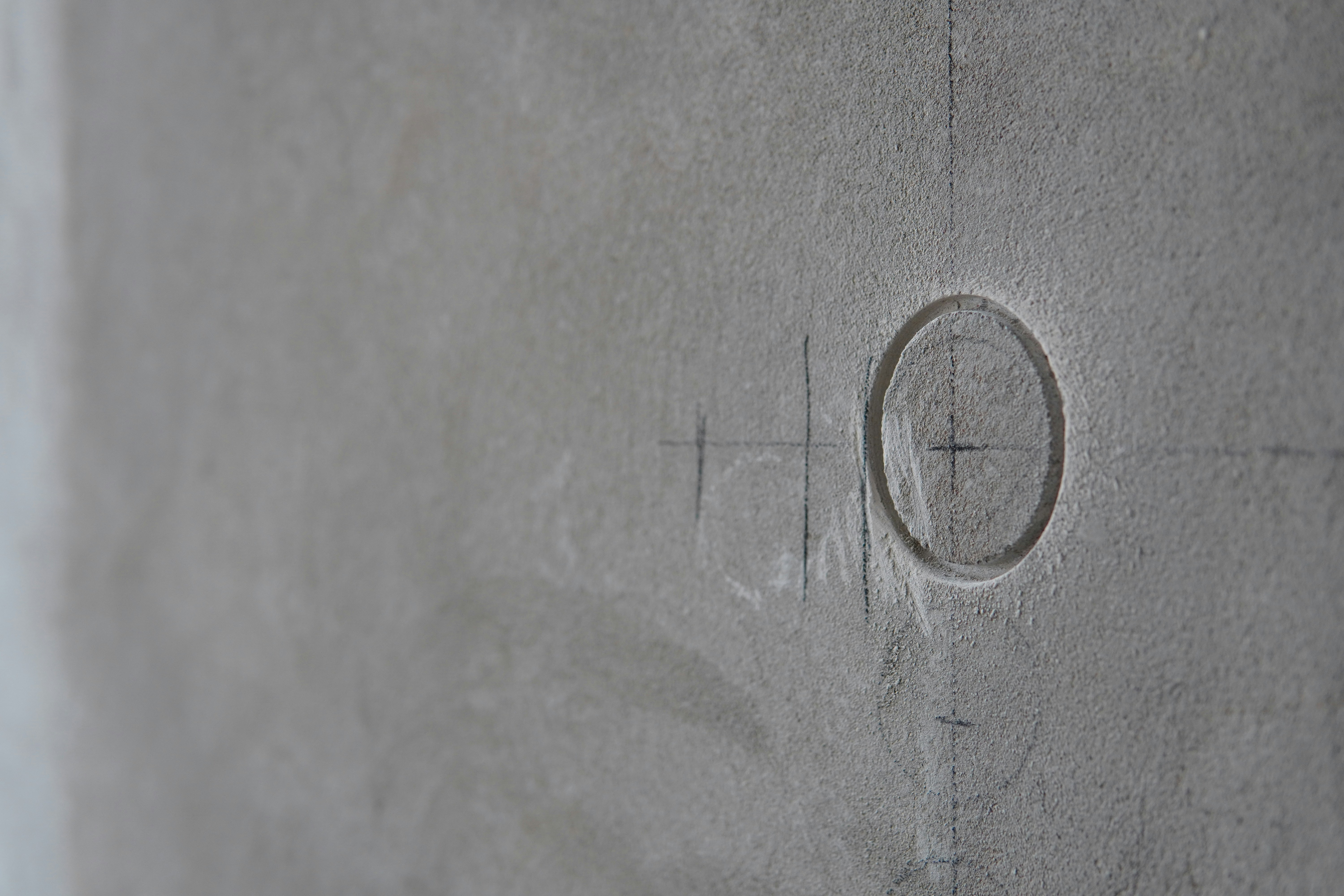 a close up of a cement wall with a cross on it