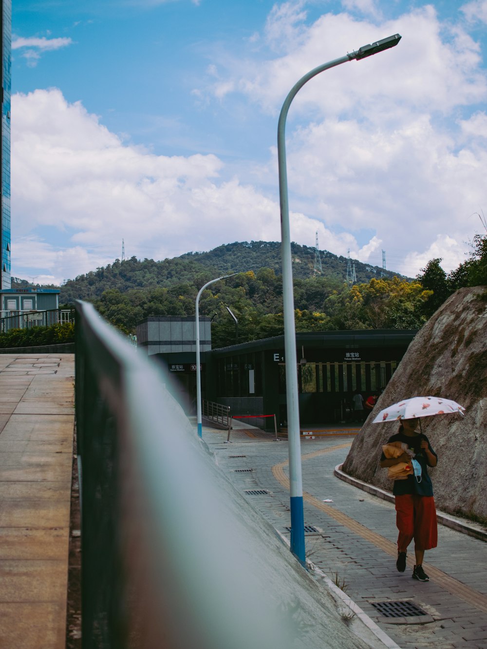 woman in brown coat holding umbrella walking on sidewalk during daytime