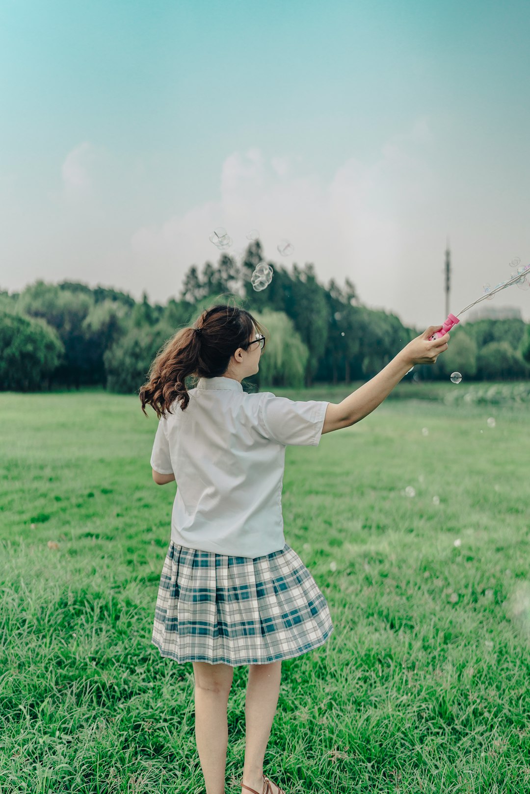 woman in white shirt and black and white plaid skirt holding green and black stick