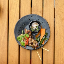 A vibrant plate of satay skewers garnished with fresh herbs and a rich dipping sauce.