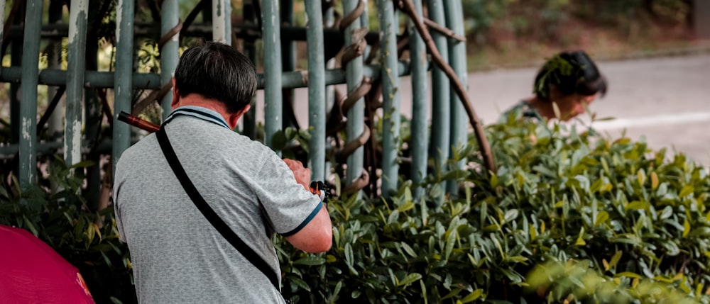 man in gray t-shirt standing near green plants during daytime