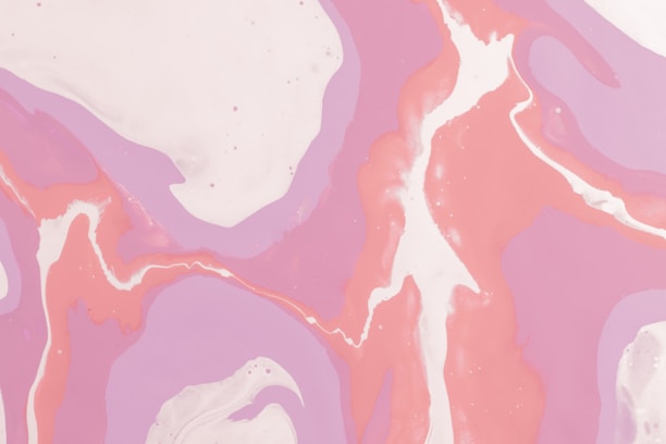 Abstract swirls of pastel pink, purple, and white create a flowing, marbled pattern. The colors blend seamlessly, forming a fluid and organic design reminiscent of liquid or smoke.