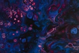 Close-up of a swirling alcohol ink artwork glowing with rich blues and purples.