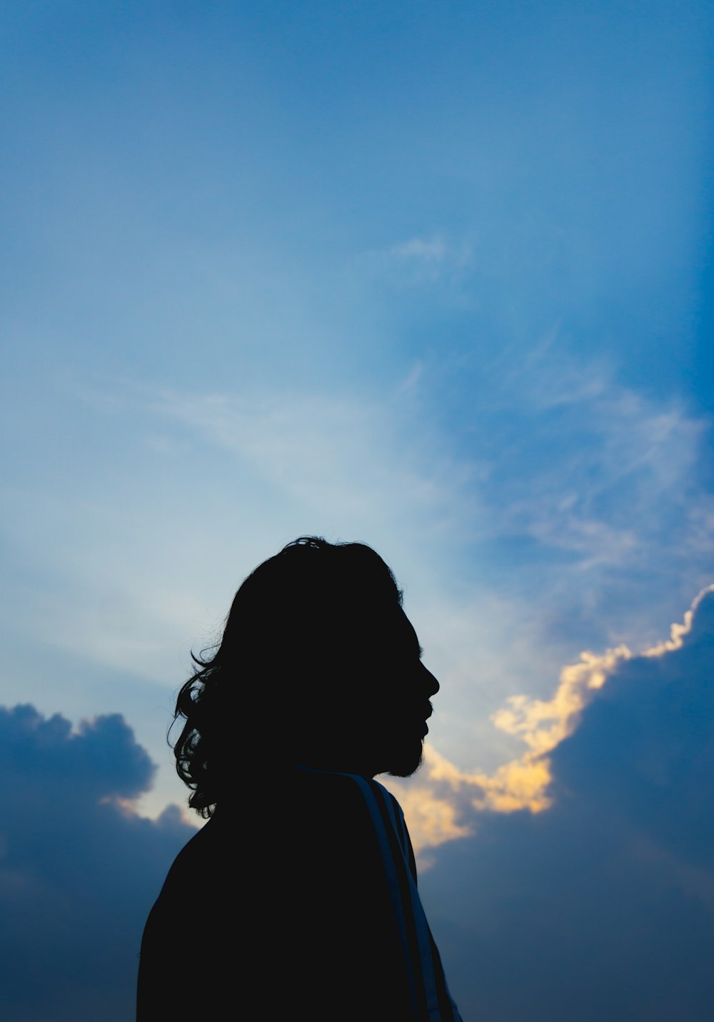silhouette of woman under blue sky during daytime