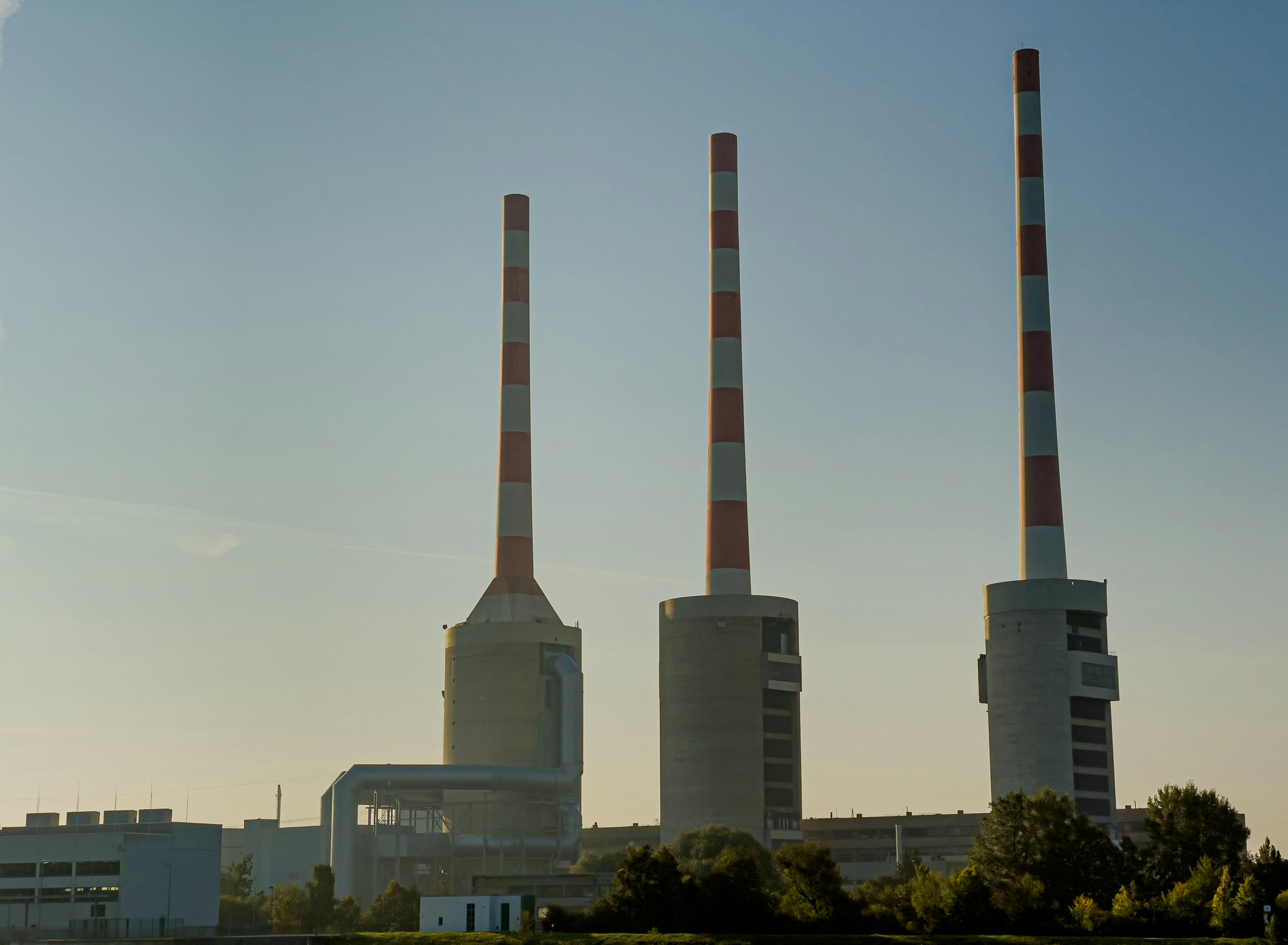 a factory with three smoke stacks in front of it