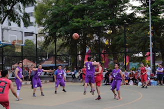 A vibrant basketball game in action under glowing gym lights, with players wearing deep purple and gold jerseys.
