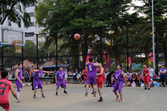 A vibrant basketball game in action under glowing gym lights, with players wearing deep purple and gold jerseys.