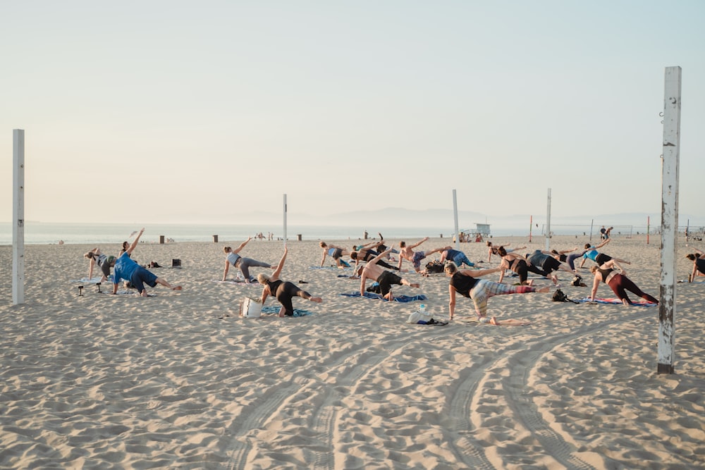 a group of people doing yoga on the beach