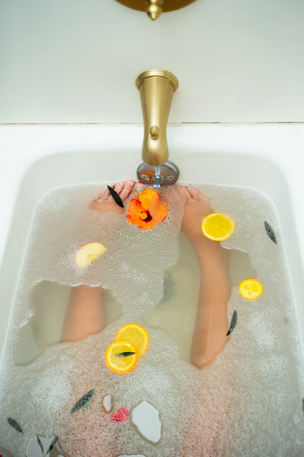 uma criança em uma banheira com laranjas e uma torneira