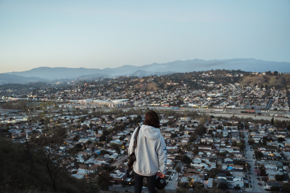 Une femme debout au sommet d’une colline surplombant une ville