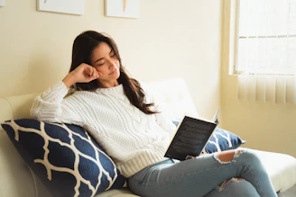 una mujer sentada en un sofá usando una computadora portátil