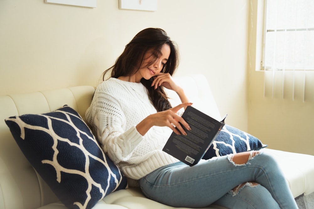 a woman sitting on a couch reading a book