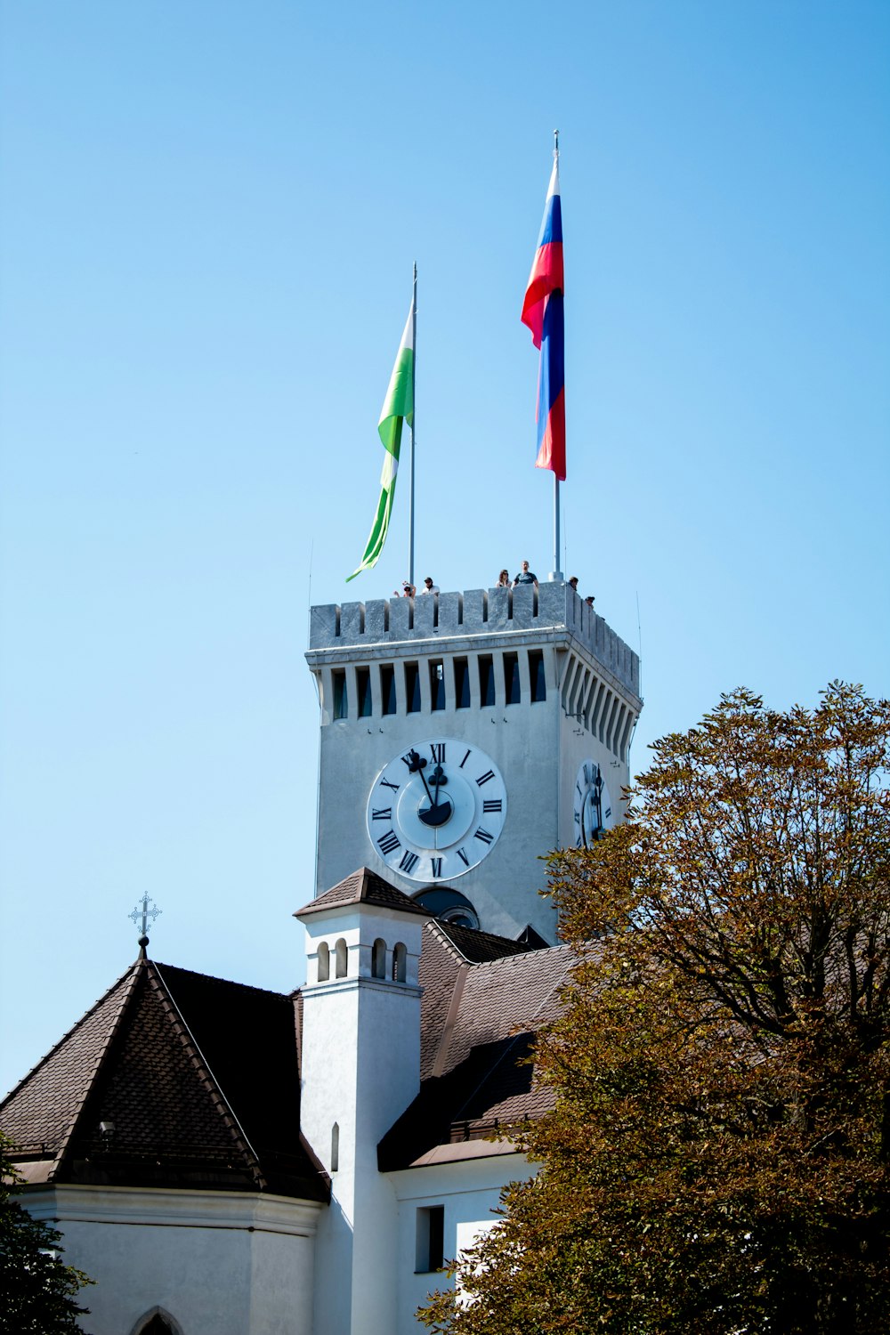 a clock tower with two flags on top of it