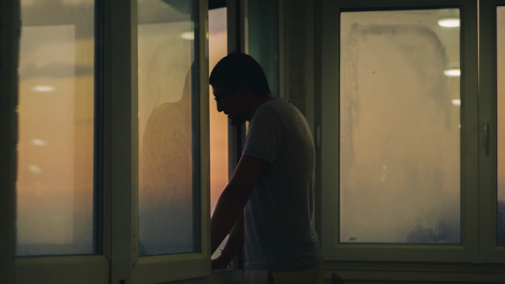 a man standing in front of a window next to a cat