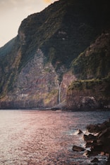 green and brown mountain beside sea during daytime