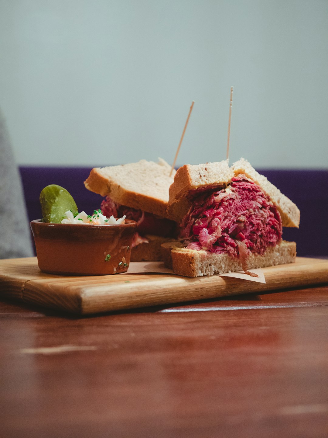 sliced bread with ham and green vegetable on brown wooden chopping board