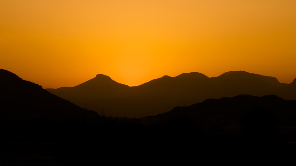 the sun is setting over a mountain range