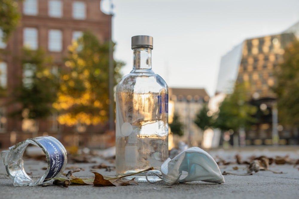 a bottle of water sitting on the ground next to a trash can