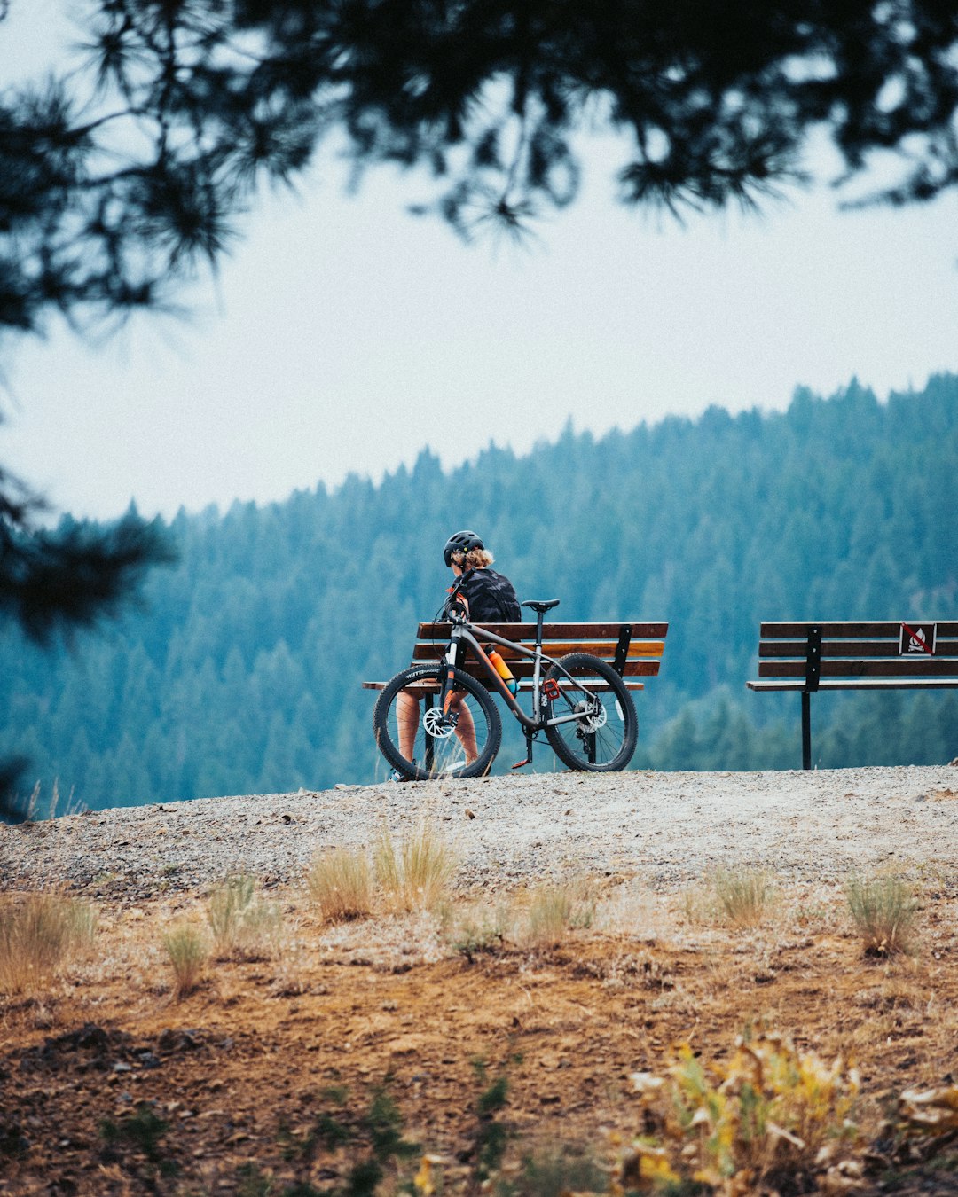 man in brown jacket sitting on bench near body of water during daytime