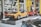A collection of vintage cars on display in an automotive showroom, featuring a prominent yellow sports car and a red sports car with its gull-wing doors open. The cars are showcased on elevated platforms, surrounded by other classic car models and various automobile memorabilia.