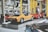 A collection of vintage cars on display in an automotive showroom, featuring a prominent yellow sports car and a red sports car with its gull-wing doors open. The cars are showcased on elevated platforms, surrounded by other classic car models and various automobile memorabilia.
