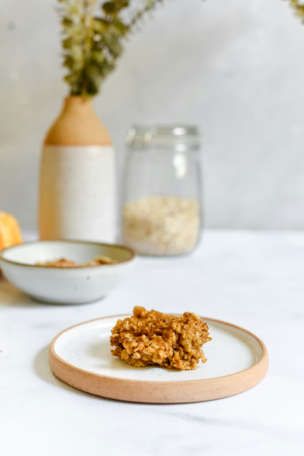 a white plate topped with granola next to a vase of flowers