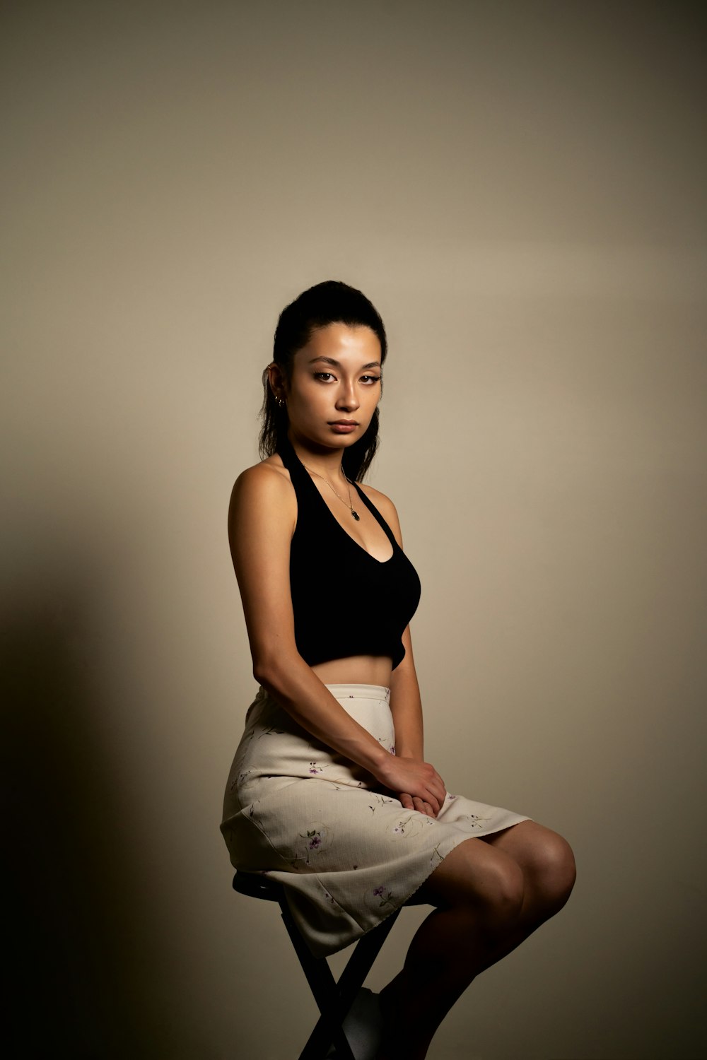 woman in black tank top and white pants sitting on white textile