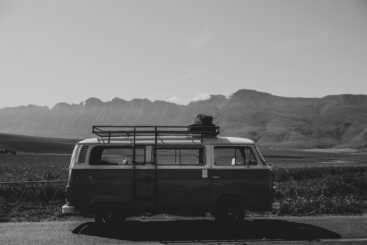 a black and white photo of a van with a surfboard on top