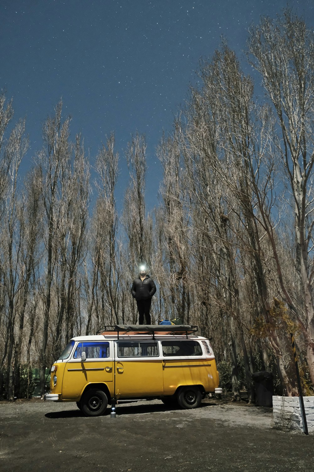 a yellow van parked in a parking lot next to trees