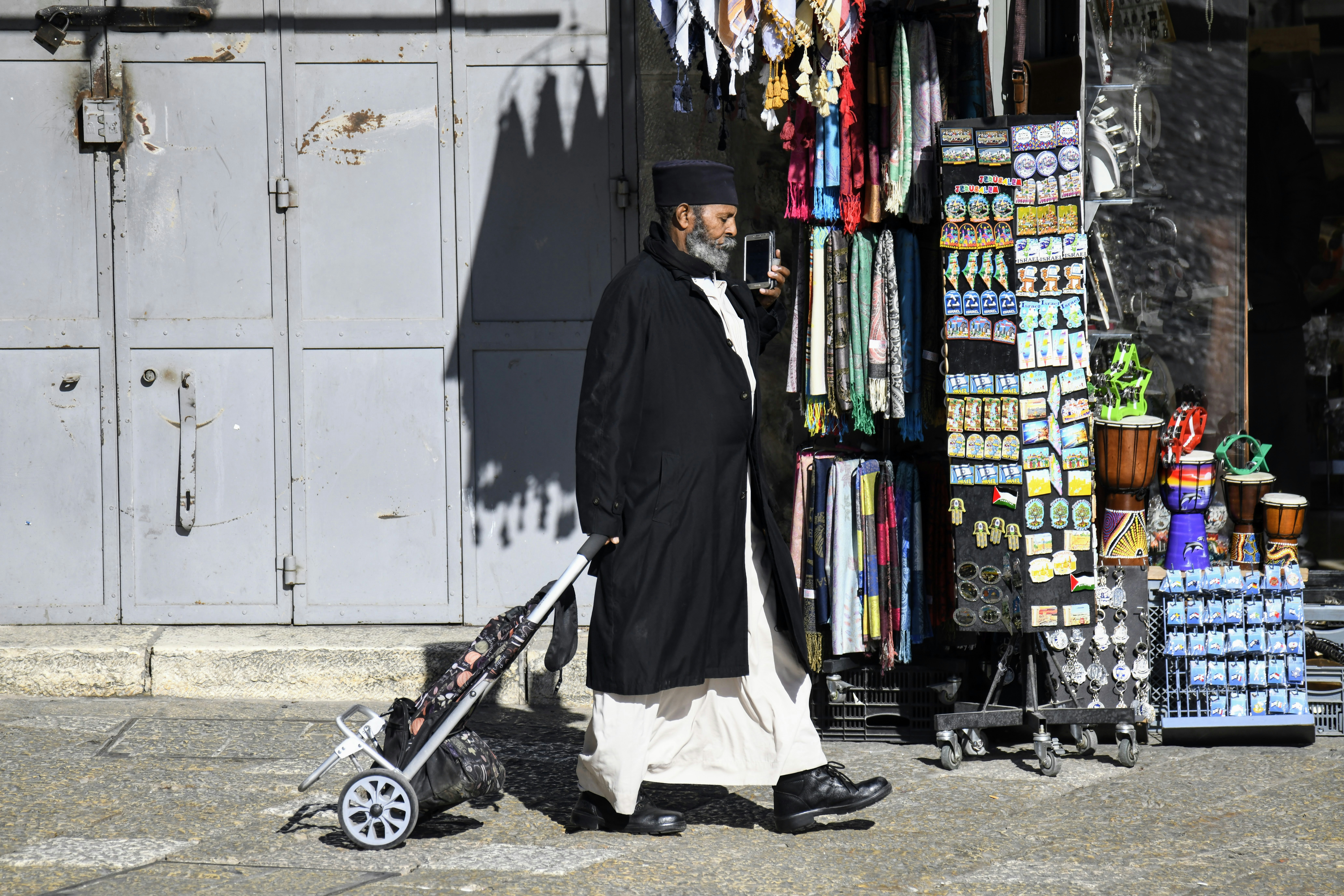 Scène de vie quotidienne montrant un homme religieux marchant avec une poussette près de la porte de Jaffa.
