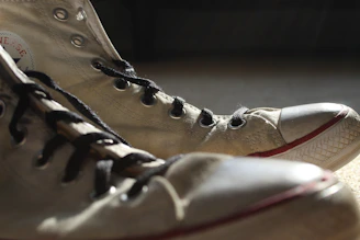A close-up of a pair of well-worn vintage sneakers resting on a wooden floor, sunlight casting warm tones.