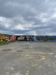 Panoramic view of a mixed-media artwork illustrating cracked walls and forgotten streets under stormy skies.