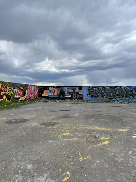Panoramic view of a mixed-media artwork illustrating cracked walls and forgotten streets under stormy skies.