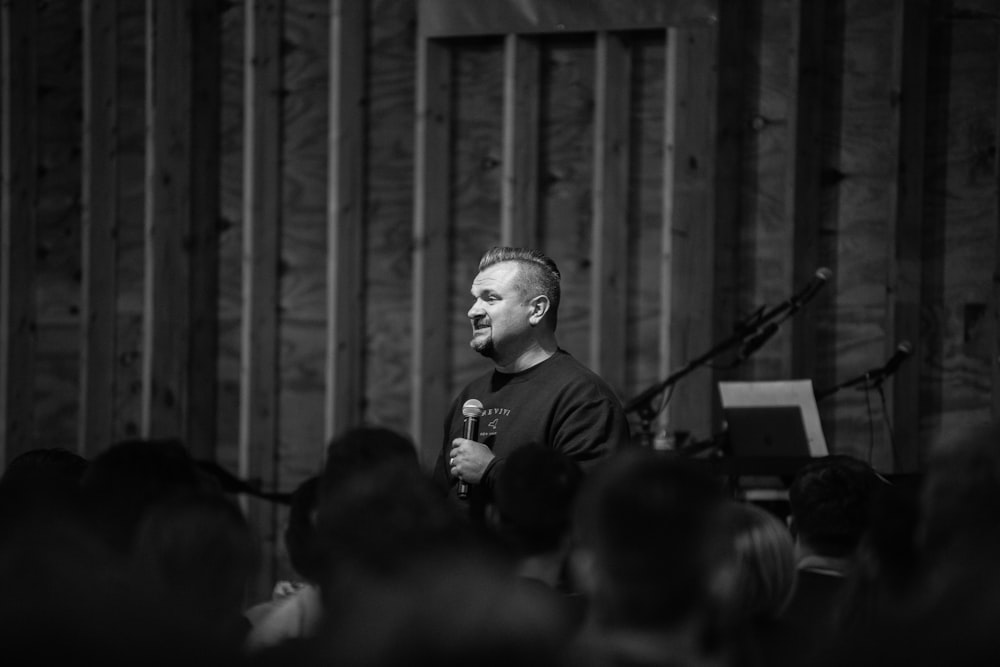 a man standing in front of a crowd holding a microphone