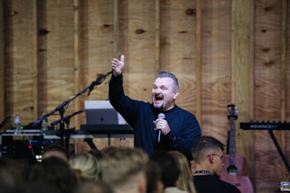 a man standing in front of a crowd holding a microphone