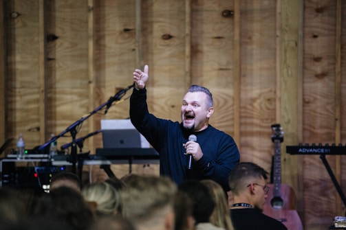 a man standing in front of a crowd holding a microphone
