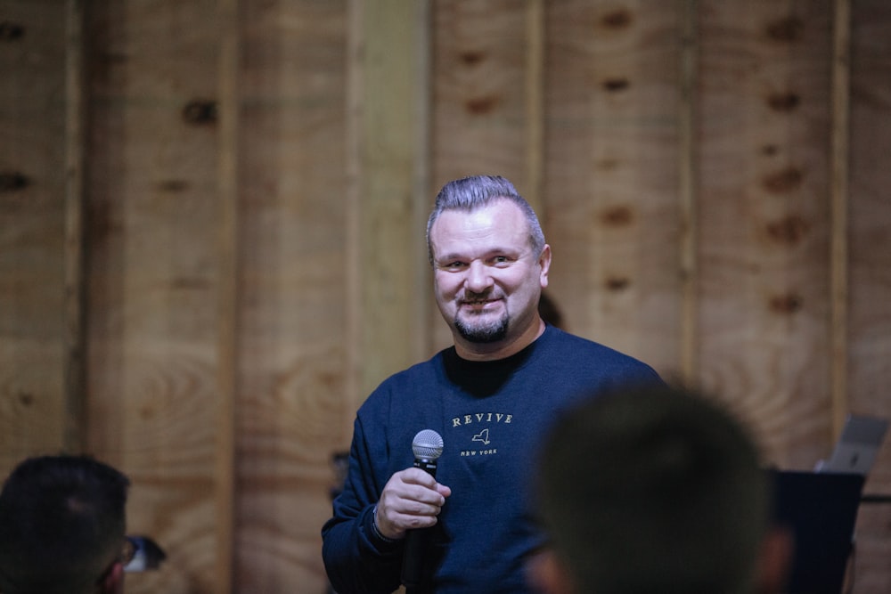 a man holding a microphone in front of a group of people