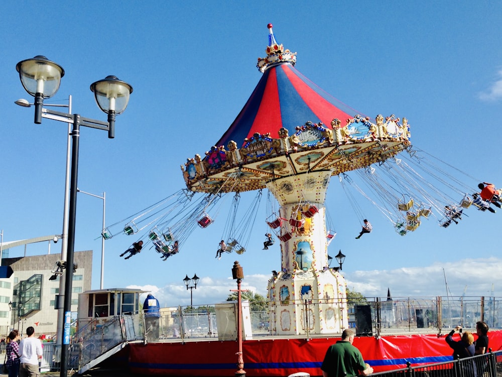 people standing on red and blue carousel during daytime