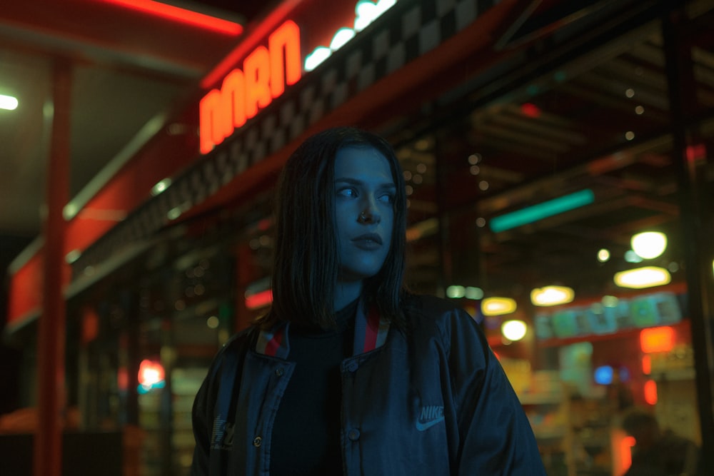 woman in blue jacket standing near red and black building